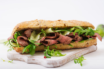 Sandwich of whole wheat bread with roast beef, cucumber and arugula.