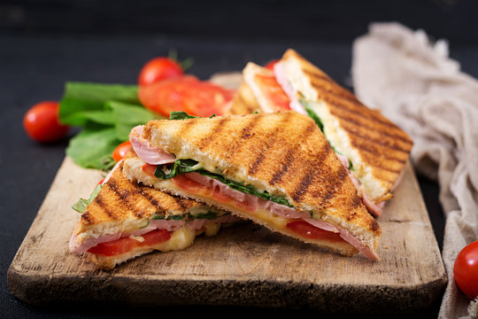 Club sandwich panini with ham, tomato, cheese and basil.