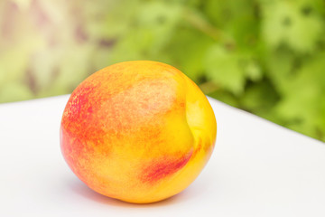 one fresh peach nectarine on the white table on natural background close up
