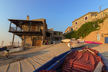 Fototapeta na wymiar Mediterranean traditional fishing boats on a ramp and lovely houses in Valldemosa harbor with sunset colors