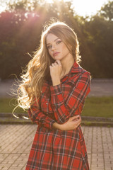 Naklejka premium Fashion portrait of stylish blonde model in trendy dress posing in rays of sun