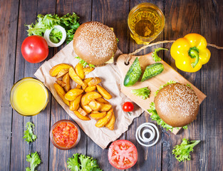 Fresh homemade burgers, fried potatoes, beer and juice served on wood table