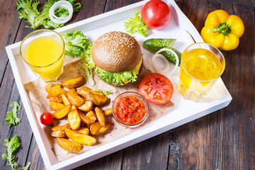 Fresh homemade burgers, fried potatoes, beer and juice served on white tray