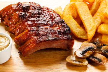 Barbecued ribs with vegetables on cutting board 