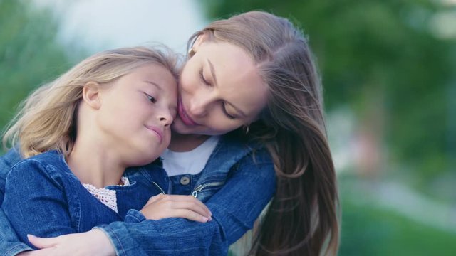 Hugging mother and daughter outdoors