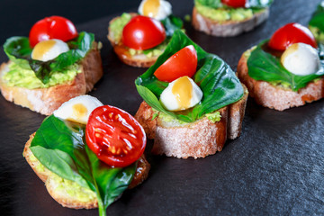 tapas with avocado, boiled quail eggs and Basil with teriyaki sauce on a black granite surface table
