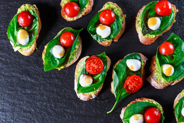 tapas with avocado, boiled quail eggs and Basil with teriyaki sauce on a black granite surface table