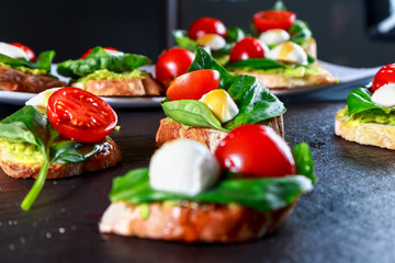 tapas with avocado, boiled quail eggs and Basil with teriyaki sauce on a black granite surface table