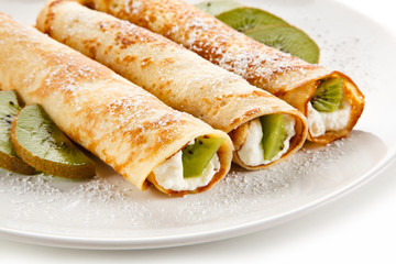 Crepes with kiwi and cream on white background 