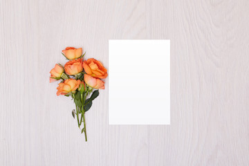 Creative mock up layout made of roses  with copy space on table homemade flat lay. Empty sheet of paper. Mockup with a card and orang rose