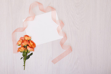 Creative mock up layout made of roses  with copy space on table homemade flat lay. Empty sheet of paper. Mockup with a card and orang rose