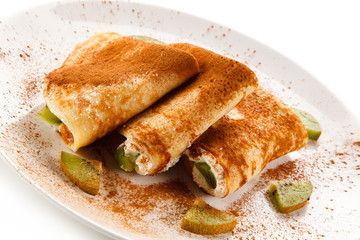 Crepes with kiwi and cream on white background