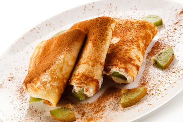 Crepes with kiwi and cream on white background 
