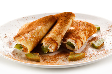 Crepes with kiwi and cream on white background 