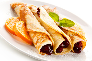 Crepes with cherries and cream on white background 