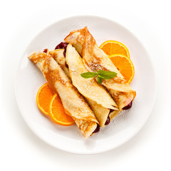 Crepes with cherries and cream on white background 