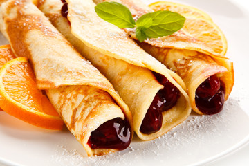 Crepes with cherries and cream on white background 