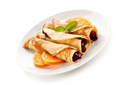Crepes with cherries and cream on white background 