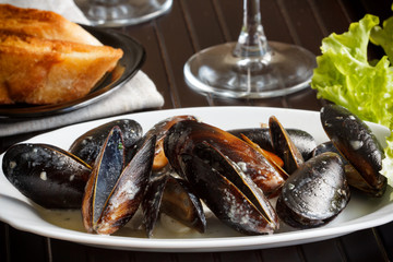 Mussels in creamy sauce on dark table surface in a cafe