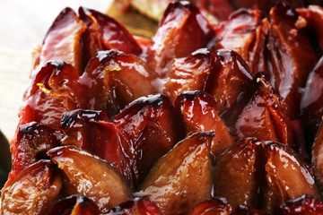 rustic plum cake on wooden background with plums around