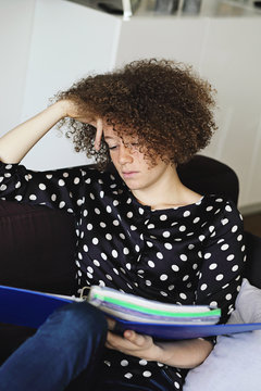jeune et jolie femme rousse &eacute;tudiant ses cours dans un divan &agrave; la maison