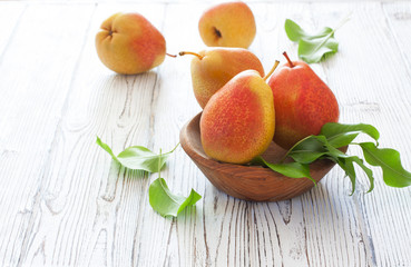 Ripe pears in wood bowl on a white wood background