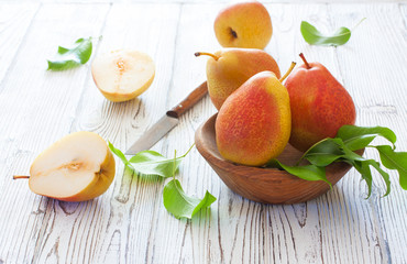 Ripe pears in wood bowl on a white wood background