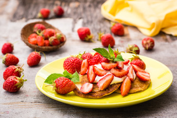 Fritters with yogurt, sliced strawberries and mint leaves on a plate