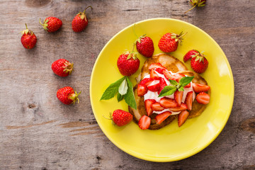 Fritters with yogurt, sliced strawberries and mint leaves on a plate. Top view