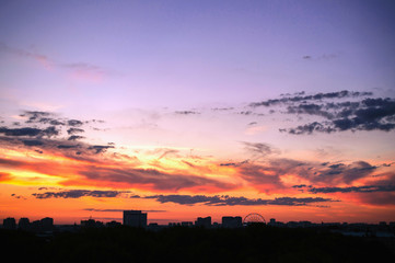 Fototapeta premium Clouds at sunset against backdrop of silhouettes houses a big ci