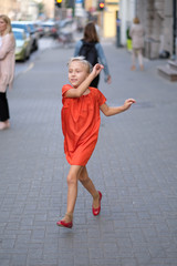 A girl is running along the sidewalk of a city street