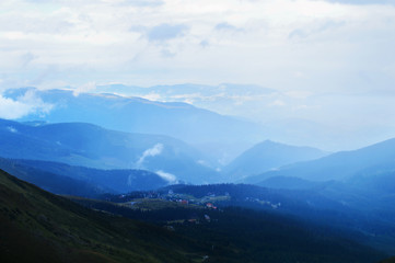 Fototapeta premium Blue mountain ridges and small town in the mountains
