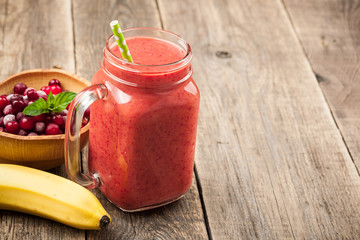 Banana-cranberry smoothie mug and ingredients on wooden table