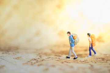 Fototapeta premium Two traveler miniature people figures with backpack standing and walking on world map. Travel and Journey concept.