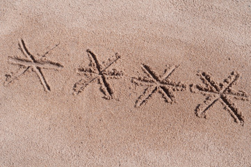 Stars of pin code drawn on brown sand on the beach in sunny day