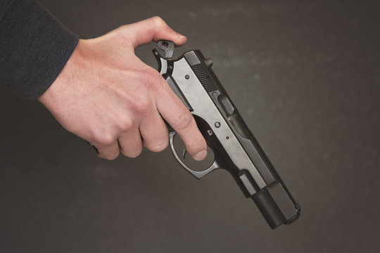 Man's hand holding gun over dark background