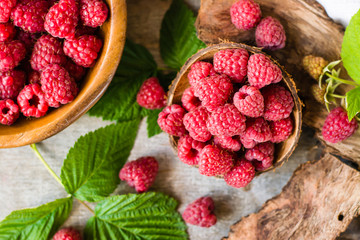 Raspberry in a bowl and in a plate, berries and leaves on a shabby  wood. Top view