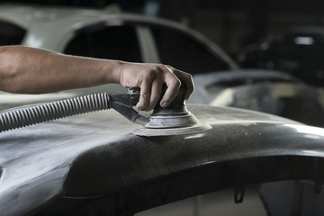 Auto body repair series: Closeup of mechanic sanding car bumper
