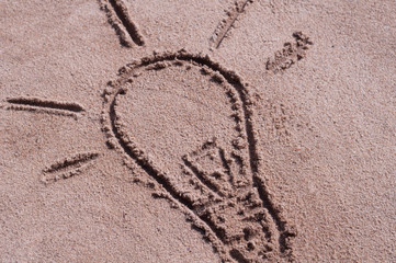 Bulb drawn on brown sand on the beach in sunny day