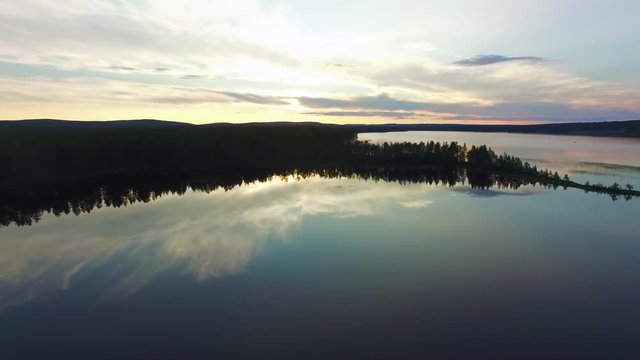 Aerial view of lake at sunset. North Sweden landscape flying over lake and forest