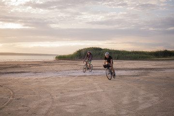 Twoo young male on a touring bicycle with backpacks and helmets  in the desert on a bicycle trip 