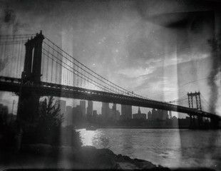Fototapeta na wymiar Wet plate of the Manhattan Bridge at sunset, looking towards Lower Manhattan from Brooklyn Bridge Park. Views of Manhattan Bridge and New York City skyline from Brooklyn black and white.
