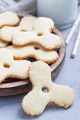 Homemade shortbread cookies made in trendy spinner toy form and glass of milk, vertical