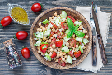 Chickpea salad with cherry tomatoes, cucumber, basil and onion with citrus dressing, horizontal, top view
