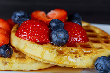 Breakfast waffle with fresh blueberries, strawberries and maple syrup