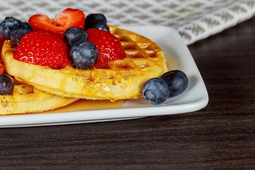 Belgian waffles with strawberries, blueberries and syrup, homemade healthy breakfast