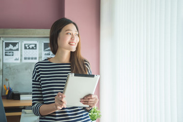 Beautiful asian woman smiling while using tablet computer