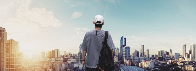 Obraz na płótnie Canvas Panoramic a man with backpack standing at sightseeing city view in sunrise