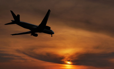 Fototapeta na wymiar Airplane is landing on sunset.