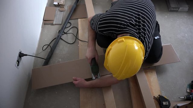 Professional male worker cutting laminate board with fretsaw